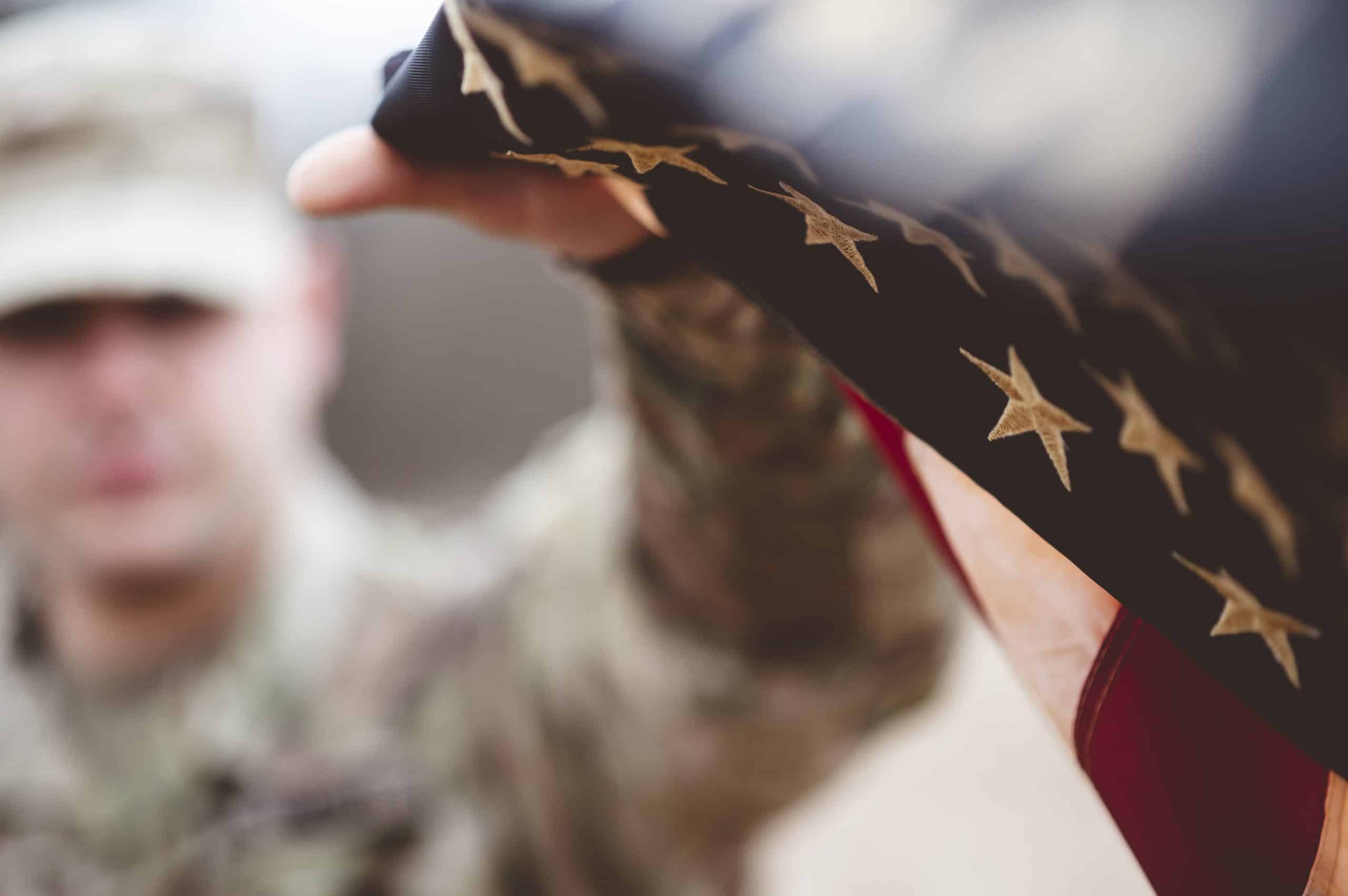 Shallow focus shot of an American soldier holding the American flag