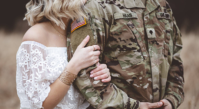 Service member and military spouse embracing in a field